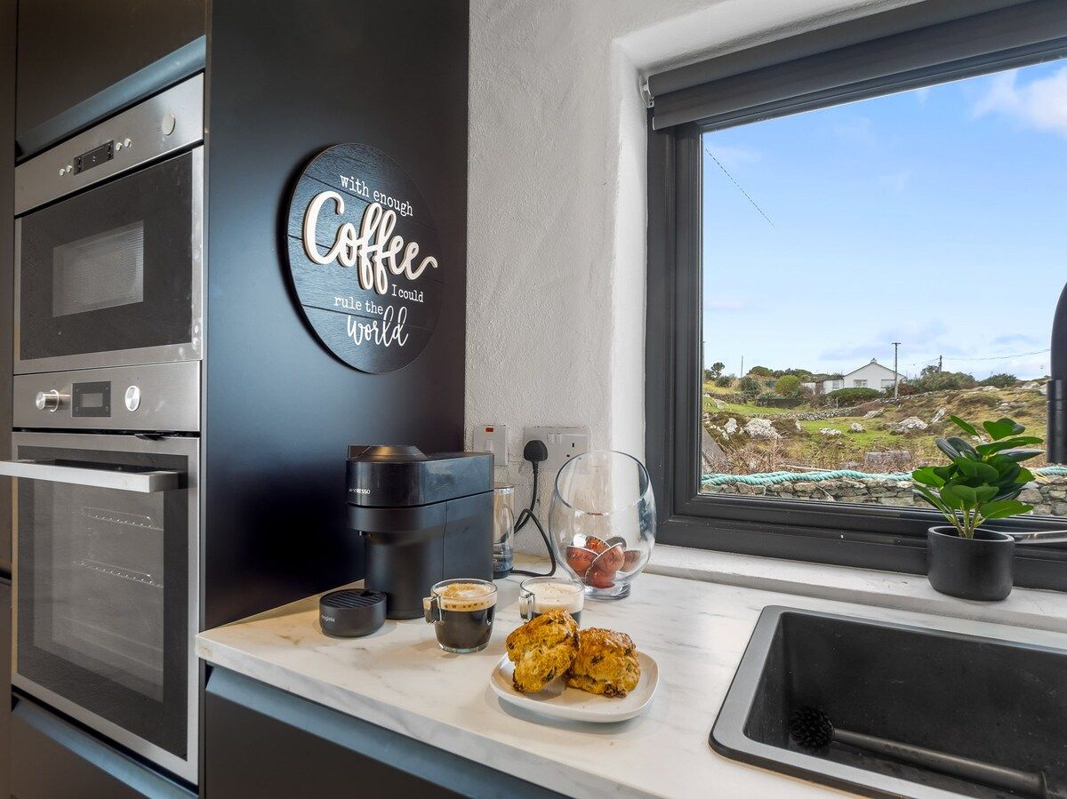 Una cocina moderna con estación de café, que incluye cafetera, tazas y pasteles.