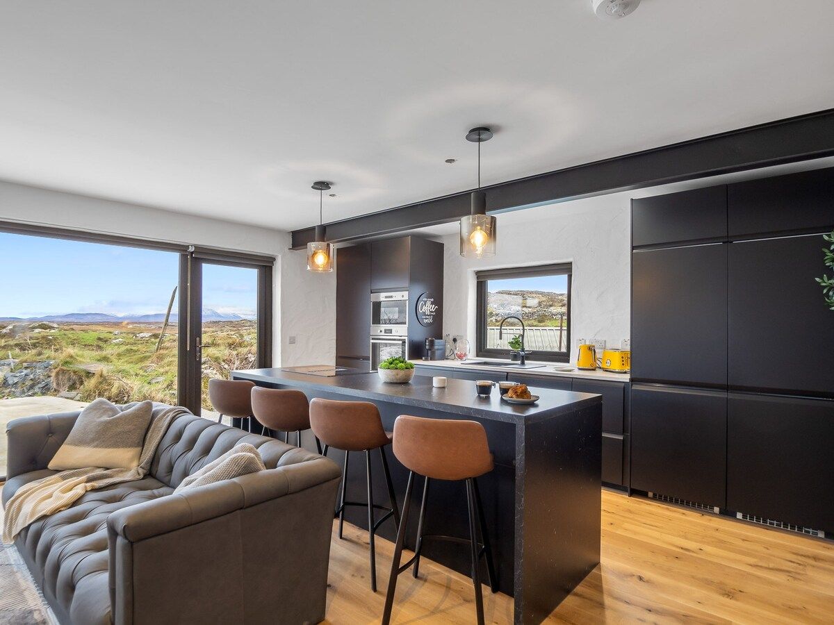 Una cocina moderna con barra, ventanas amplias y vistas al exterior.