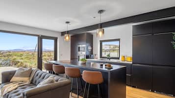 Una cocina moderna con barra, ventanas amplias y vistas al exterior.