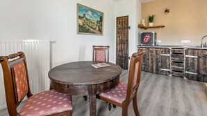 A dining area with a round wooden table and chairs, a radiator, a painting, a wooden door, and a kitchen counter with a Rolling Stones logo. - Apartment 'Gutgemacht' with Shared Terrace, Garden, and Wi-Fi (Sankt Annen)