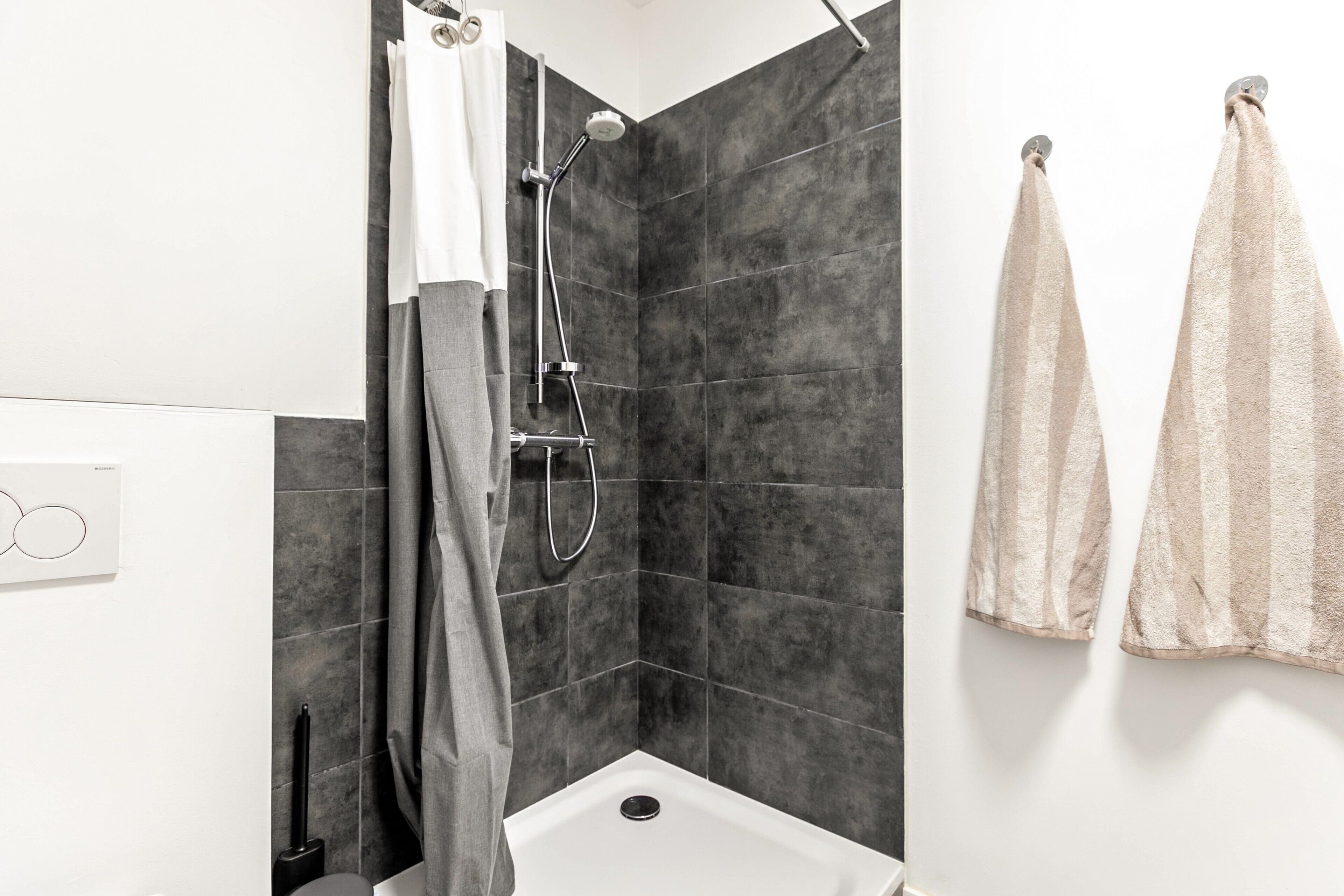 A modern bathroom with a shower, a toilet, and a sink.