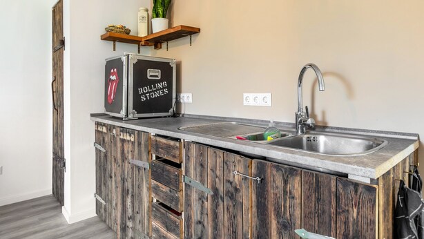 A kitchen with a rustic wooden cabinet, a rolling stones branded toaster, a sink, and a shelf with plants and kitchen items. - Apartment 'Gutgemacht' with Shared Terrace, Garden, and Wi-Fi (Sankt Annen)