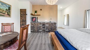 A compact room with a bed, a dining table, a kitchenette, and a painting on the wall. - Apartment 'Gutgemacht' with Shared Terrace, Garden, and Wi-Fi (Sankt Annen)