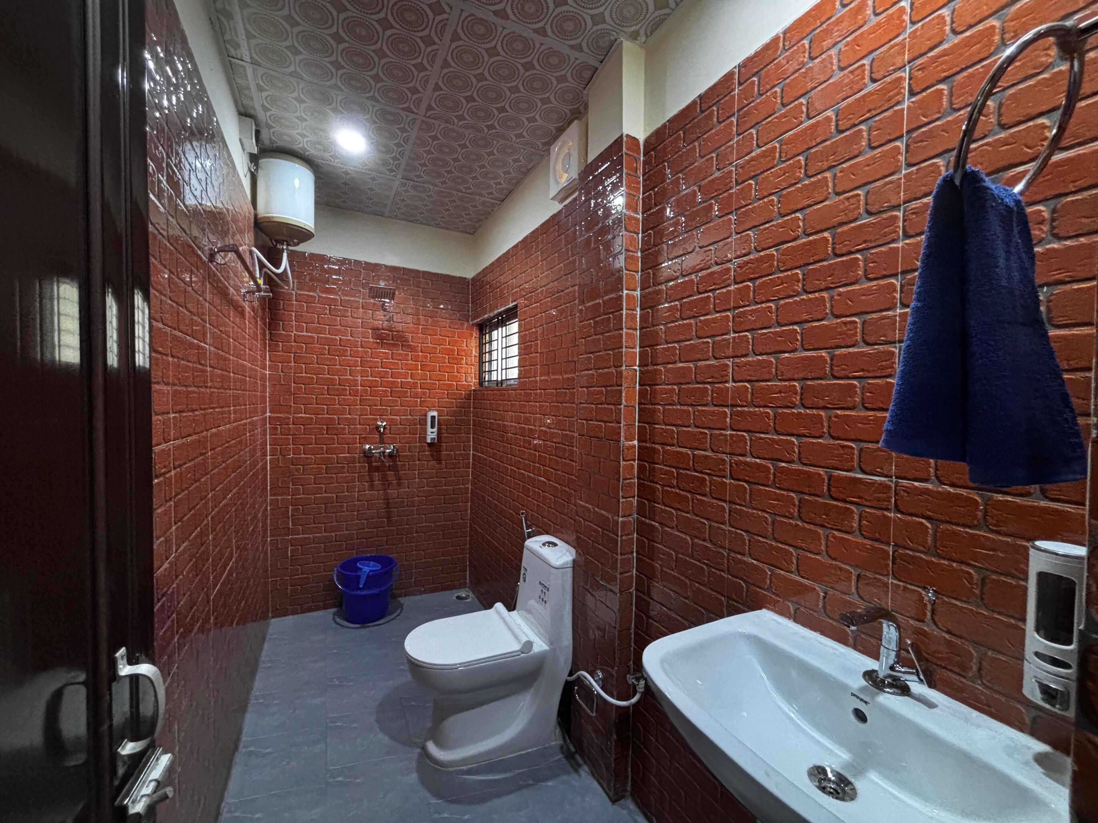 A bathroom with red brick walls, a white sink, and a toilet.