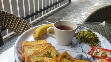 Una mesa con una tostada, un plátano, una taza de té y guisantes verdes.