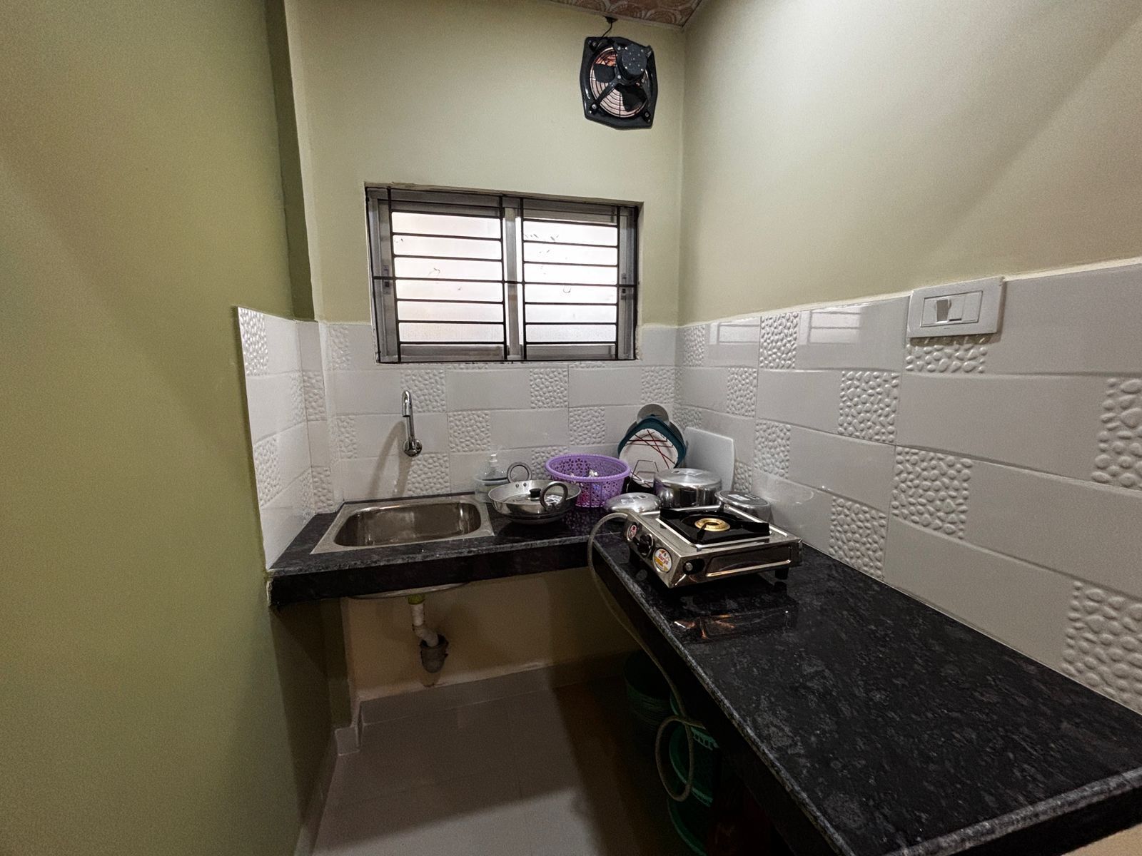 Una pequeña cocina con un lavamanos, una ventana y una estufa.