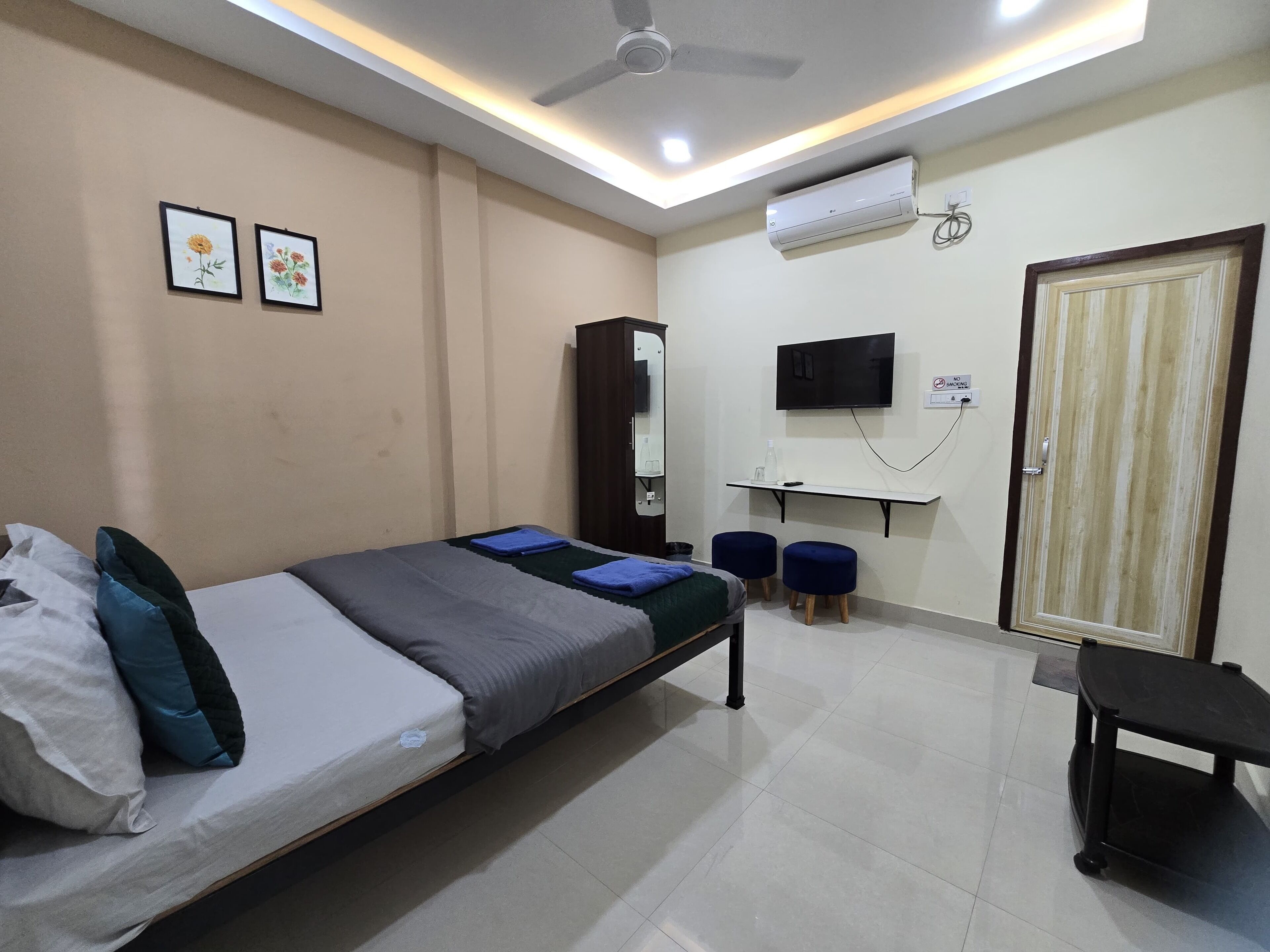 A bedroom with a bed, a desk, a TV, and a wardrobe.