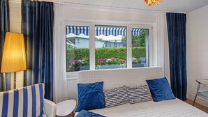 A room with a bed, a chair, a table, and a window with curtains.