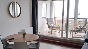 Une pièce avec une table ronde, deux chaises, une petite plante et un miroir au mur.
