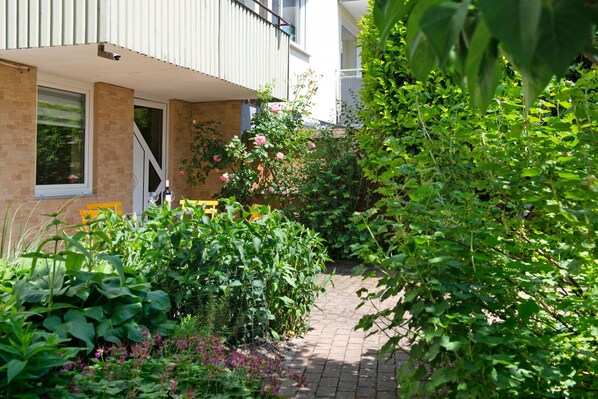 A garden pathway leading to a building with a brick facade and a window.