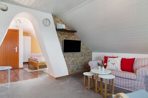 A cozy room with a stone wall, a flat-screen TV, a sofa, and a small table.