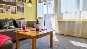 Una sala de estar con un sofá, una mesa de centro de madera, una botella de vino y una copa.