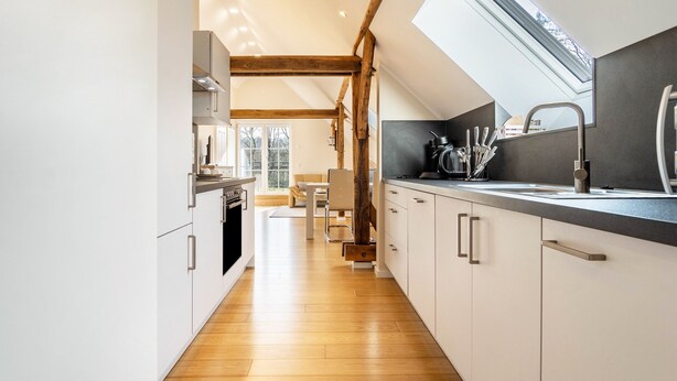 Een moderne keuken met houten balken, dakraam en uitzicht op de omgeving.