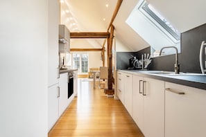 A modern kitchen with wooden beams, a skylight, and a view of the outdoors.