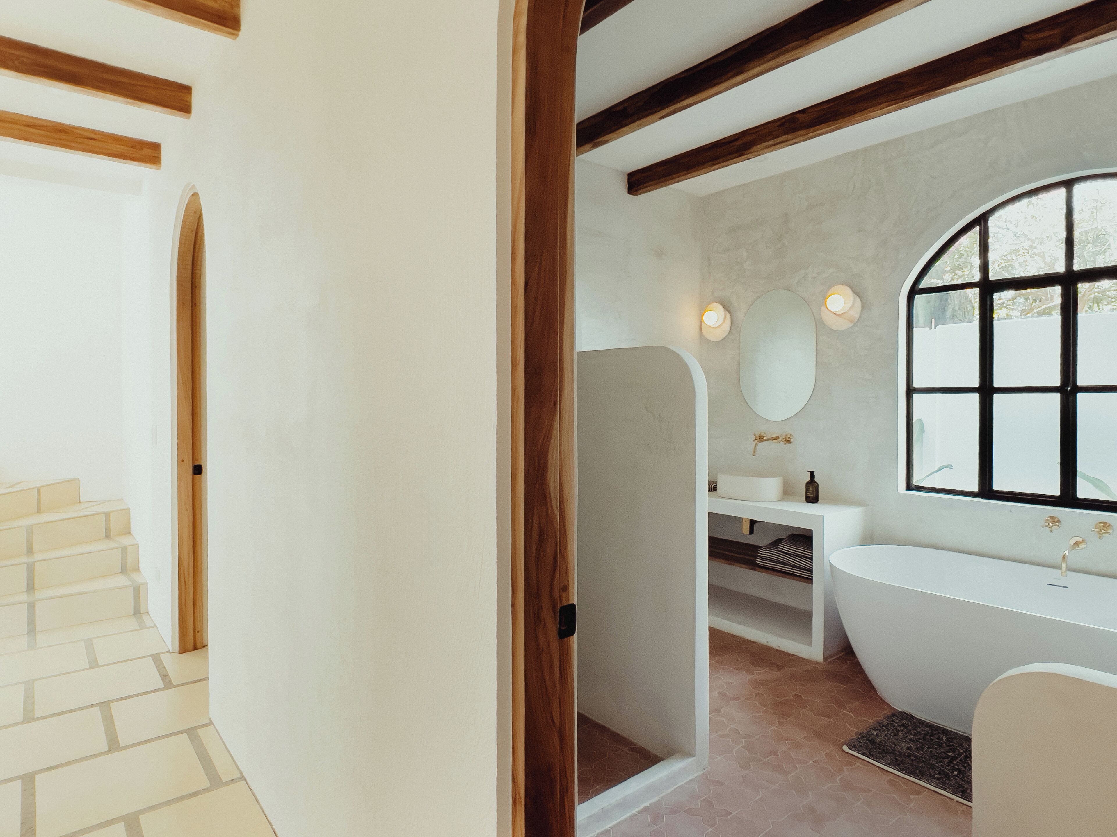 Une salle de bain avec une baignoire sur pieds, un grand miroir et une fenêtre.