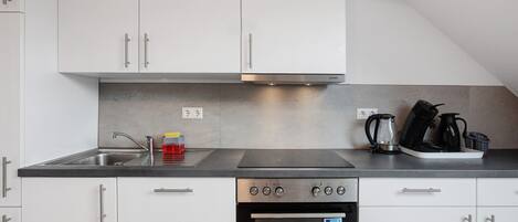 A modern kitchen with white cabinets, a stainless steel stove, and a built-in oven.