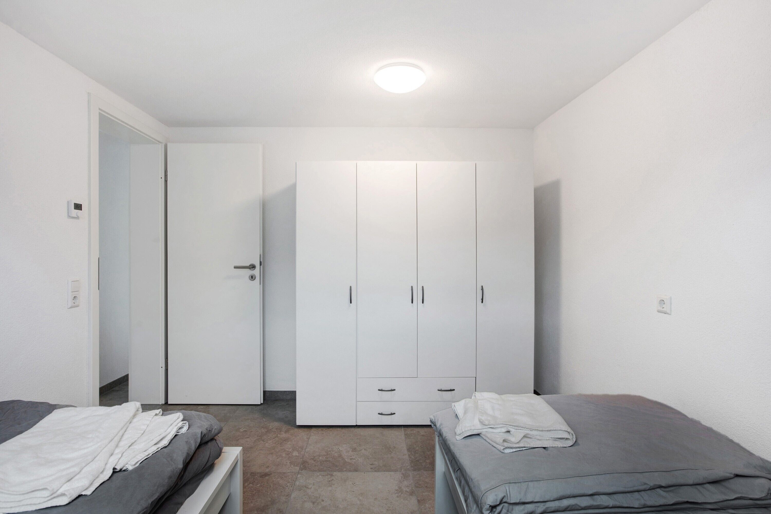 Een slaapkamer met twee bedden, een kledingkast en een deur naar een andere kamer.