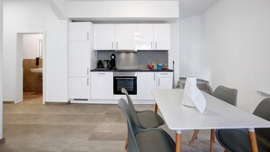 A modern kitchen with white cabinets, a stove, and a dining area with a table and chairs.