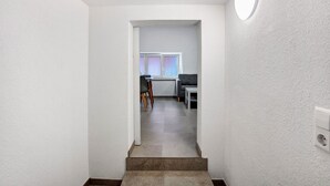 A hallway leading to a dining area with a table and chairs, a window, and a built-in light fixture.