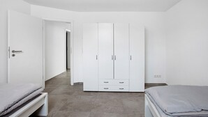 A bedroom with a bed, a wardrobe, and a door leading to another room.