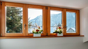 A window with wooden frames and two flower arrangements.