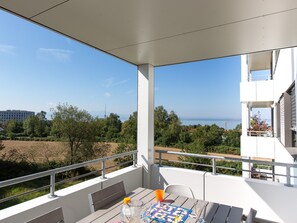 A balcony with a table, chairs, and a view of the sea and buildings. - Apartment 'Busch' with Lake View, Balcony and Wi-Fi (Friedrichshafen)
