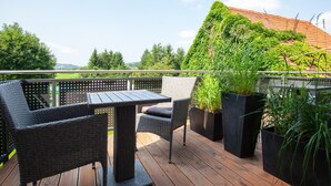 A wooden deck with wicker furniture and potted plants. - Apartment 'Vogelsberg' with Shared Terrace, Shared Garden and Wi-Fi (Wächtersbach)