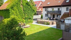 A residential property with a well-maintained lawn, a patio area with outdoor furniture, and a two-story building with a balcony. - Apartment 'Rhön' with Shared Terrace, Shared Garden and Wi-Fi (Wächtersbach)
