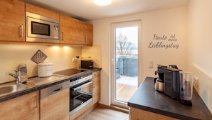 A modern kitchen with wooden cabinets, a microwave, a coffee maker, and a kettle. - Apartment 'Rhön' with Shared Terrace, Shared Garden and Wi-Fi (Wächtersbach)