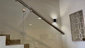 Una escalera moderna con barandillas de vidrio y decoración mural geométrica.