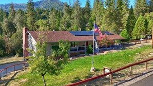 Un chalet avec un toit rouge, un mât sur lequel flotte le drapeau américain, entouré d’une forêt et d’un lac.