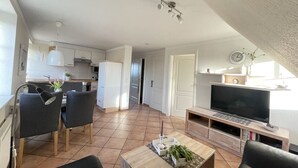 Um apartamento moderno com sala de jantar, cozinha, sala de estar e televisão.