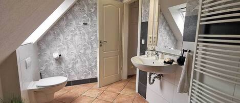 A bathroom with a toilet, sink, and towel rack.