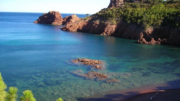 A coastal landscape with clear water, rocky outcrops, and a beach. - Village House in France with Private Pool (Bagnols-en-Forêt)