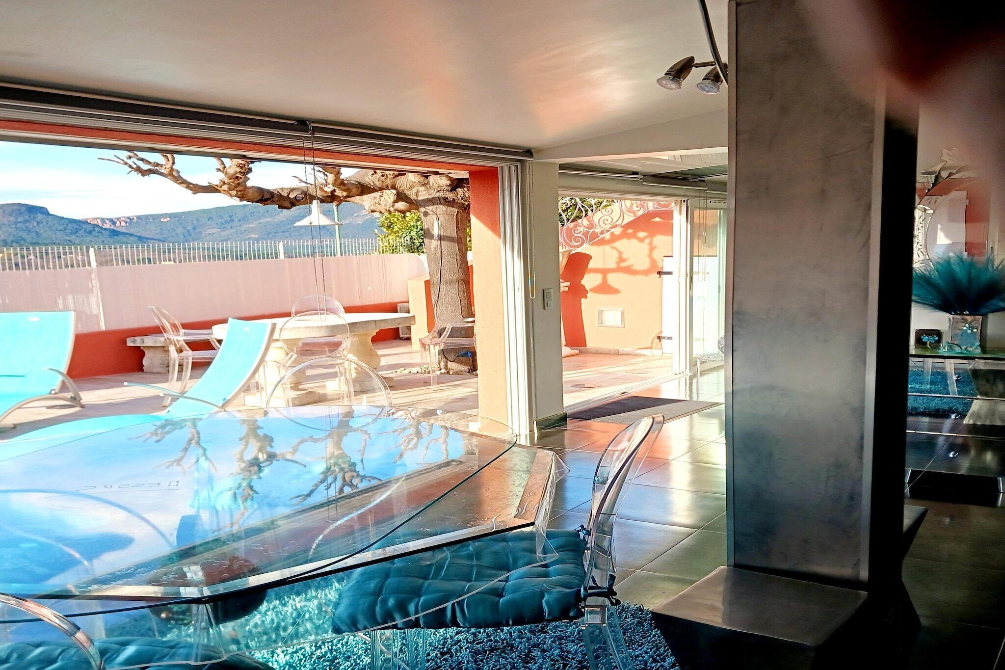 Ein modernes Interieur mit einem Glastisch, transparenten Stühlen und Blick ins Freie.