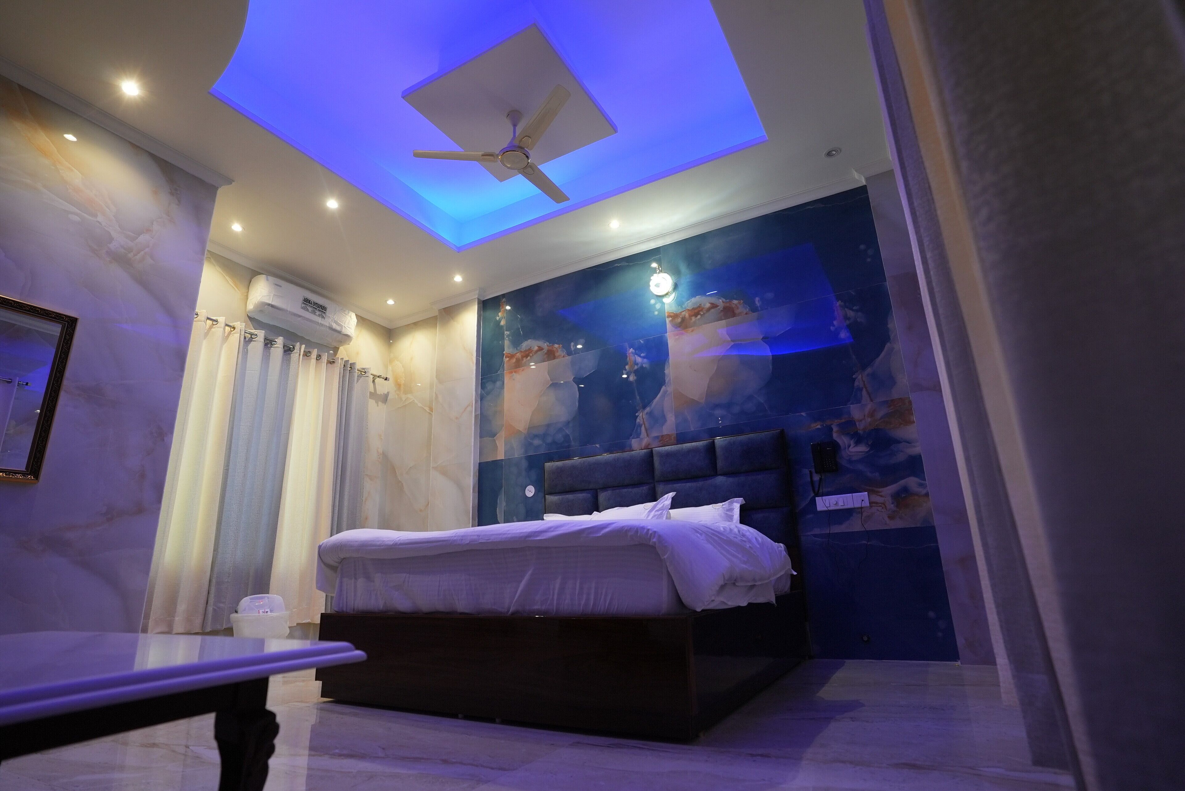 A modern bedroom with a bed, a ceiling fan, and a wall-mounted air conditioner.