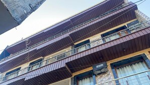 A multi-story building with a balcony on the second floor, a large wooden door, and a stone facade. - Hotel Paradise - Chandigarh (Chandigarh)