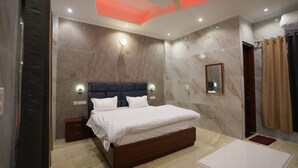 A modern bedroom with a large bed, a bedside table, a ceiling fan, and a mirror on the wall. - Hotel Paradise - Chandigarh (Chandigarh)