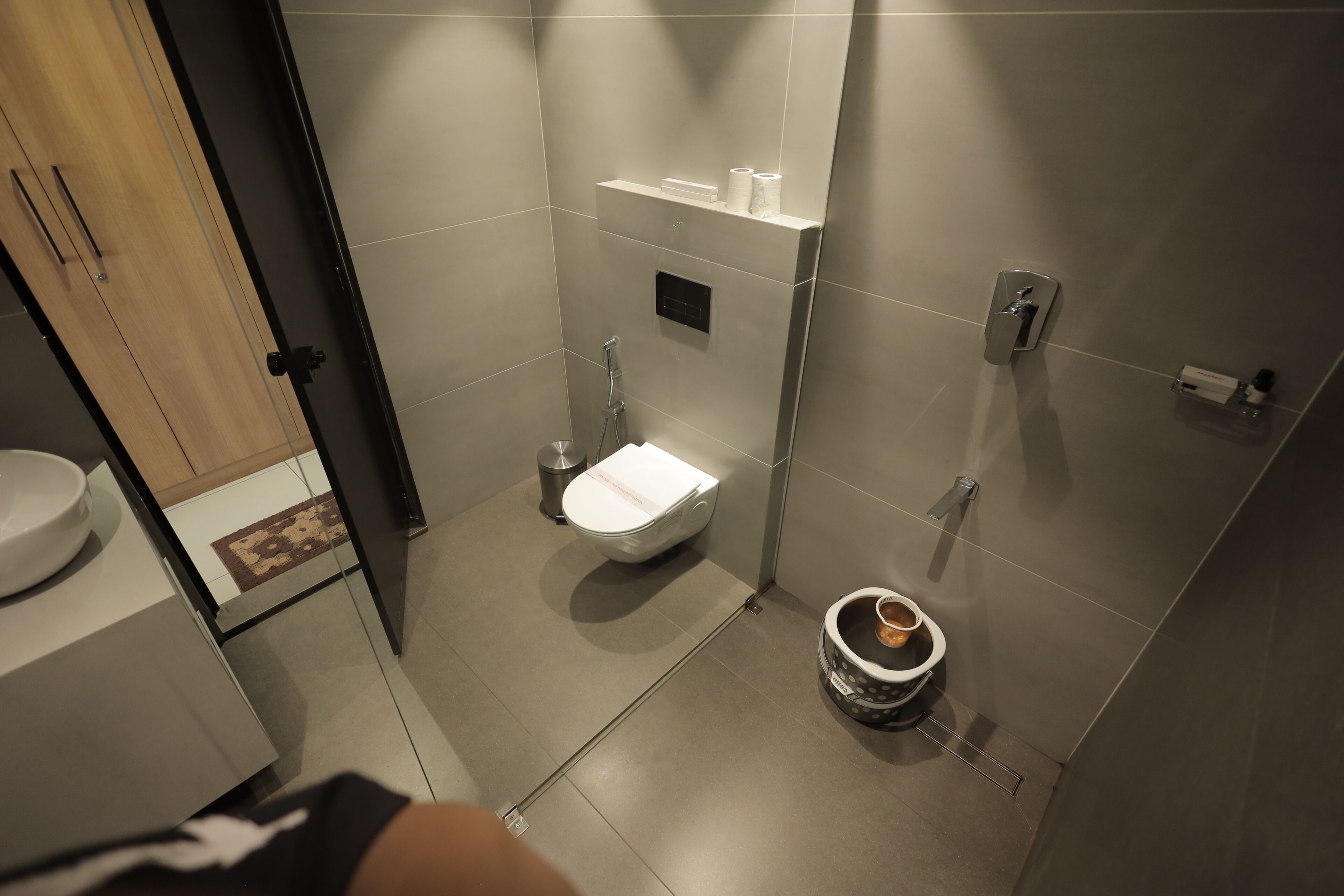 Een moderne badkamer met toilet, hygiëneslot en een prullenbak.