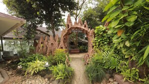 Een tuinpad dat leidt naar een rustieke boog met de tekst 'Brooke House'.