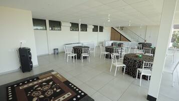 A spacious indoor area with multiple tables and chairs, a staircase, and a patterned rug.
