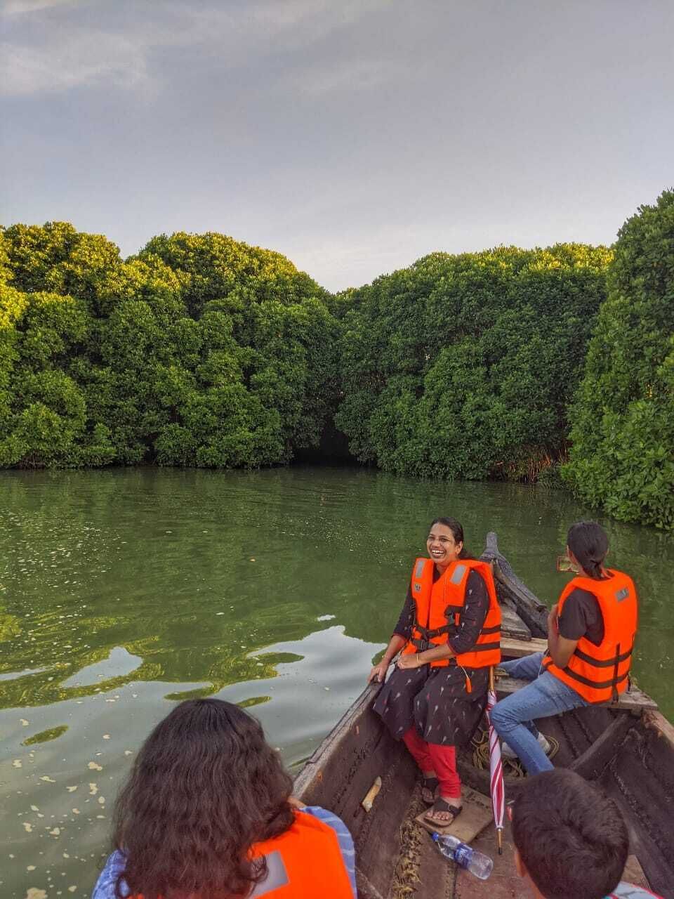 A group of people in a boat on a river surrounded by dense greenery.
