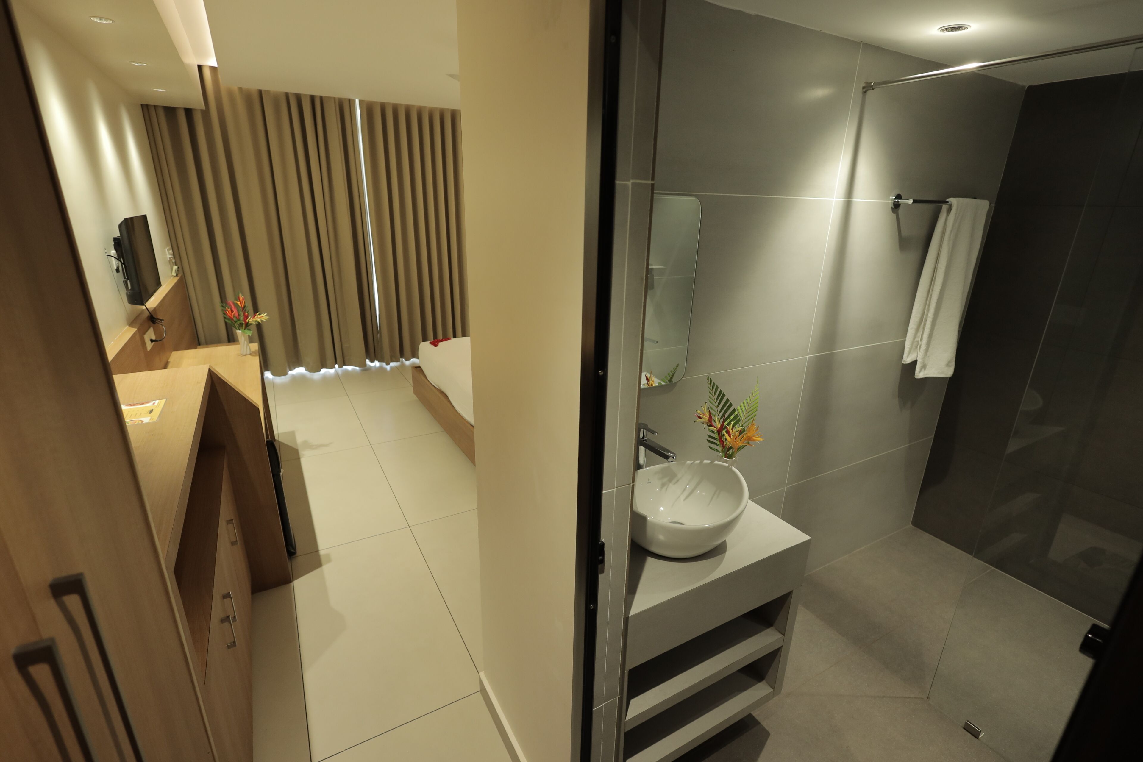 Une salle de bain moderne avec un grand miroir, un lavabo et un espace douche.