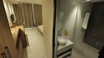 Une salle de bain moderne avec un grand miroir, un lavabo et un espace douche.