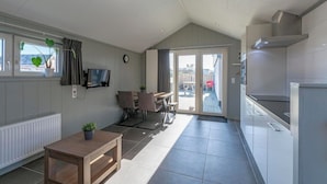 A compact kitchen with a dining area, a TV, and a window with a plant. - Beach house 't Koepeltje near dunes (Groote Keeten)