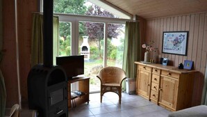 Un salon chaleureux avec une cheminée, un téléviseur, un fauteuil en osier et un meuble en bois.