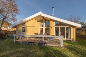 A modern house with a sloped roof, large windows, and a deck with outdoor furniture. - Ferienhaus mit Sauna im Ferienpark Mirow (Granzow)
