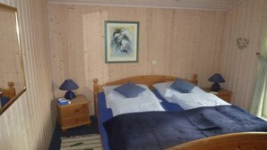 A wooden-paneled room with a bed, two nightstands, a lamp, and a framed picture on the wall.