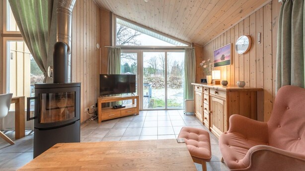 L’intérieur chaleureux d’un chalet, avec un décor en bois, une cheminée, un téléviseur et un coin repas.
