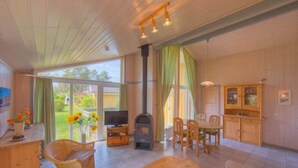 A spacious living area with a fireplace, wooden furniture, and large windows offering a view of the outdoors.